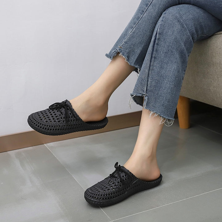 Women's black woven mules with open back, lace-up bow and flat sole, worn