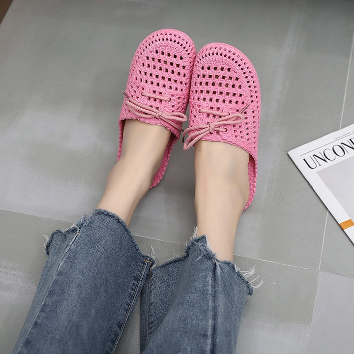 Women's pink woven mules with open back, lace-up bow and flat sole, worn