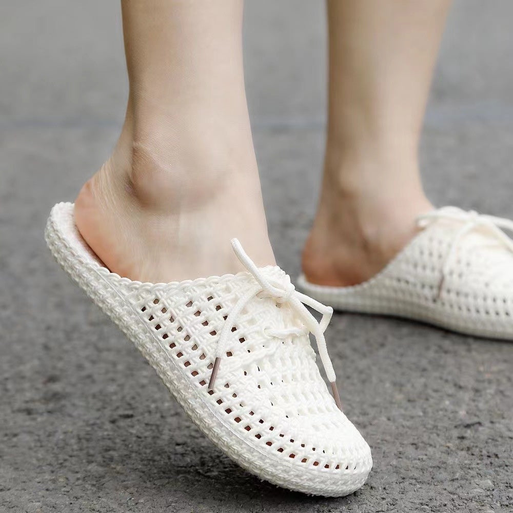 Women's white woven mules with open back, lace-up bow and flat sole, worn