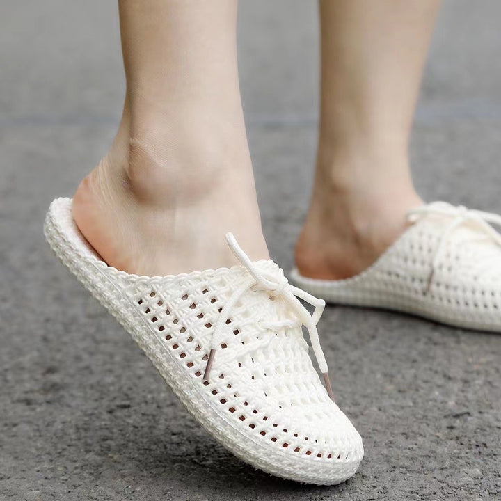 Women's white woven mules with open back, lace-up bow and flat sole, worn